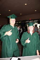 Two GBC graduates in green caps and gowns.